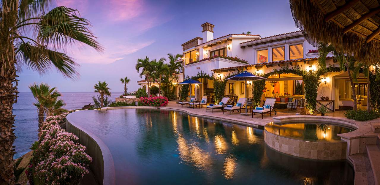 A Pool With A House And Palm Trees