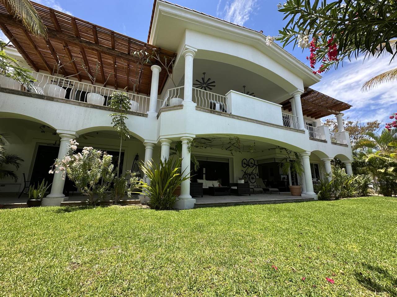 A Large White House With A Lawn And A Blue Sky