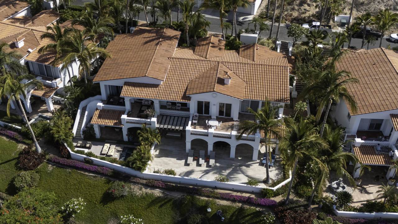 A Large White House With Orange Roof And Palm Trees
