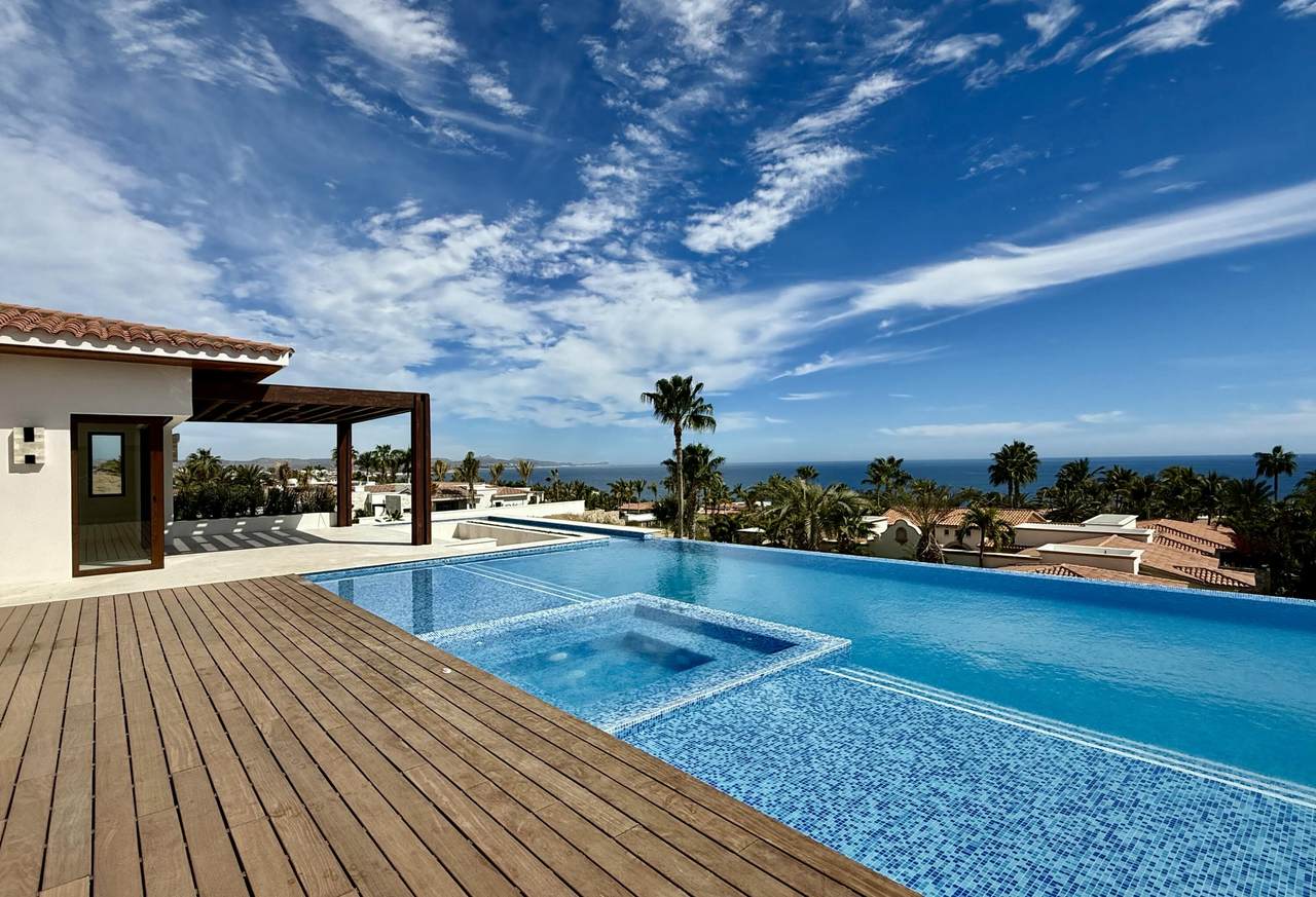 A Pool With A Deck And A Wood Deck With A Wood Deck And A Blue Sky With Clouds